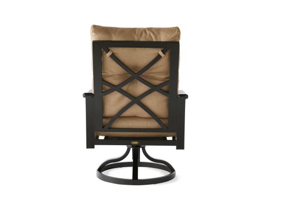 The Anthem Swivel Rocking Dining Armchair features a dark metal frame with a crisscross pattern on the backrest and a beige cushion attached by top straps. Its circular base allows for rotation.
