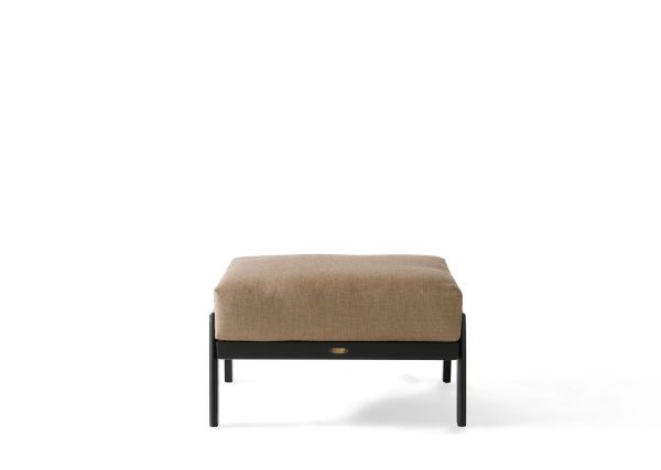The Dakoda Cushion Ottoman features a modern, rectangular tan upholstered cushion atop a sleek black metal frame. This minimalist design showcases clean lines and a low profile against a plain white background.