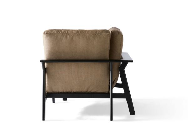 From a rear view, the Dakoda Cushion Corner Chair showcases its beige cushions and sleek black modern frame. Its minimalist design with straight lines stands out against a plain white background.