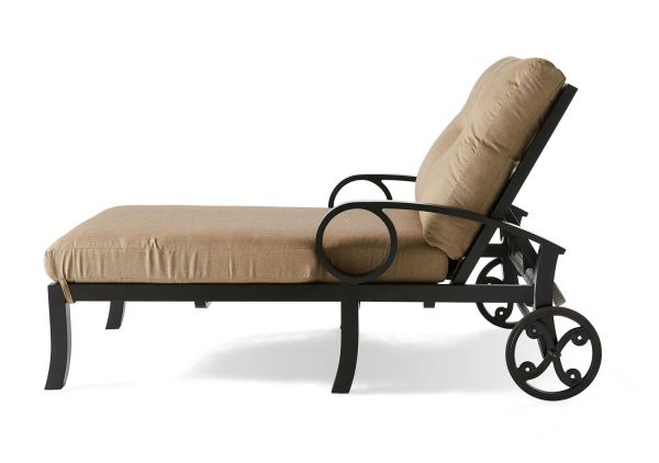 The Eclipse Oversized Chaise Lounge features a beige cushioned seat and backrest, a black metal frame with circular armrests, and two rear wheels for easy mobility. It is displayed in profile against a white background.