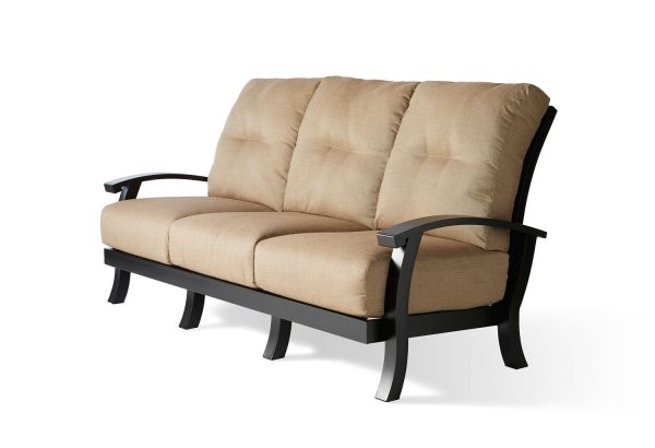 The Georgetown Cushion Sofa is a beige three-seater with plush cushions, a black metal frame, curved armrests, and legs for a modern and comfortable look. Its soft texture invites relaxation.