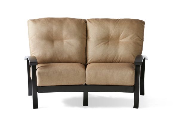 The Georgetown Cushion Crescent Love Seat features a tan, tufted upholstery with two large back cushions, complemented by black curved metal armrests and legs. Its presented against a plain white background.