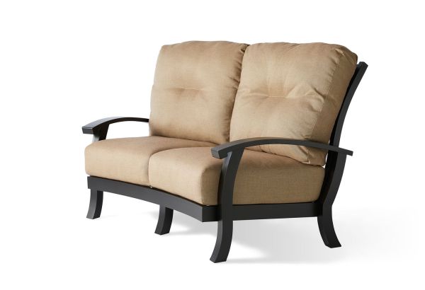 The Georgetown Cushion Crescent Love Seat is a beige loveseat with a simple, contemporary design. It features cushioned seating and backrest, complemented by dark wooden arms and frame.