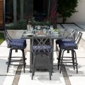 Outdoor dining set with a square glass-top table and built-in fire pit, surrounded by four chairs. The scene features glasses, a salad, and a lush garden backdrop. Paired perfectly with the M Series Armless Bar Stool to complete the experience.